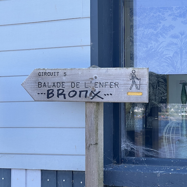 Un panneau de randonnée signalant le Chemin des Enfer et sur lequel est taggé Bronx