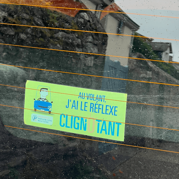 un sticker Au volant j'ai le réflexe clignotant sur un pare brise de voiture