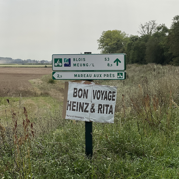 Panneau en carton Bon Voyage Heinz & Rita sous une signalisation vélo