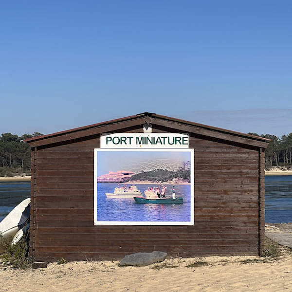 Cabanon sur une plage avec une pancarte Port Miniaturre et une vielle photo de bateau miniatures