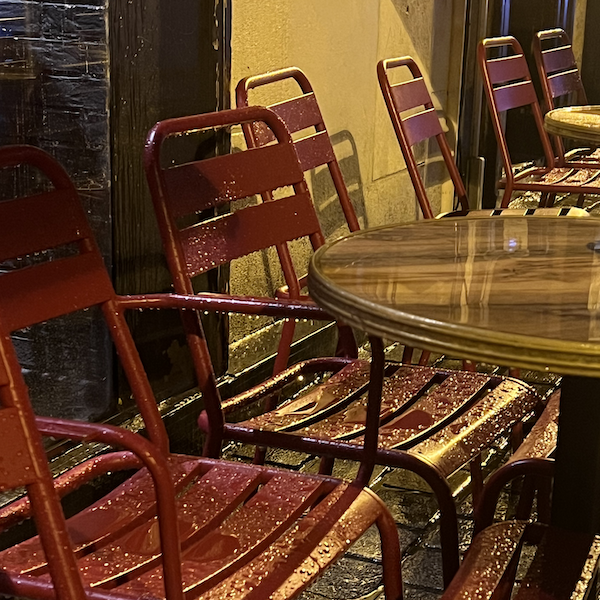 des tables et chaises d'un bar sous la pluie
